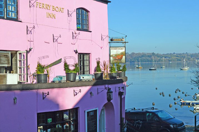 The Ferry Boat Inn, Dittisham, with boats on the water behind.