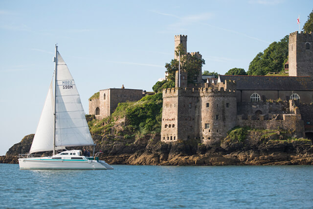 Dartmouth Town Guide - View of Dartmouth Castle across the water, with a sailing boat in the foreground