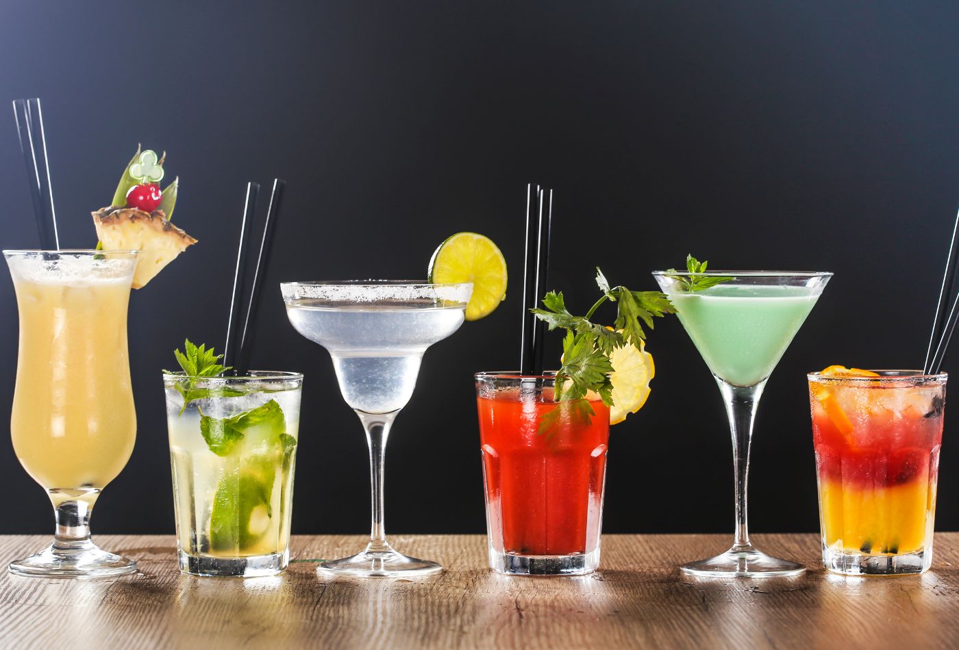 Different cocktails along a wooden bar